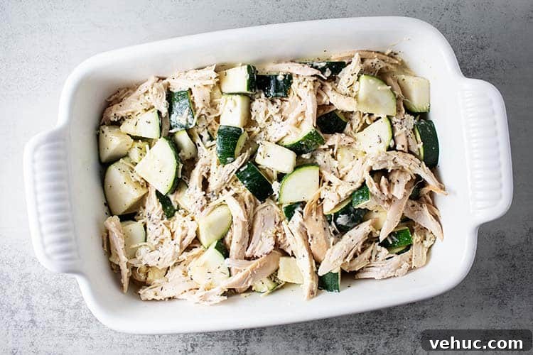 overhead view of white casserole dish with zucchini, chicken and egg mixture inside