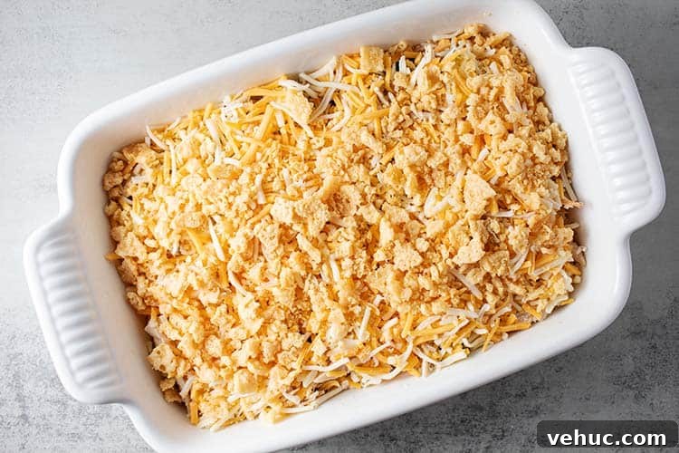 overhead view of white casserole dish with chicken and zucchini inside and topped with shredded mexican cheese