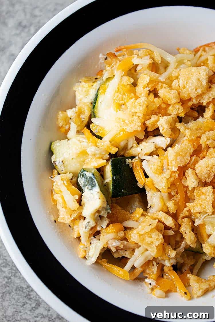 overhead view of serving of healthy keto low carb chicken and zucchini casserole in a white bowl with a black stripped rim