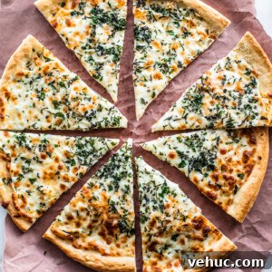 Herb & Garlic Cheese Pizza Recipe for Crispy, Flavorful Homemade Slices 7 Overhead shot of cooked herb and garlic cheese pizza cut into slices on parchment paper.