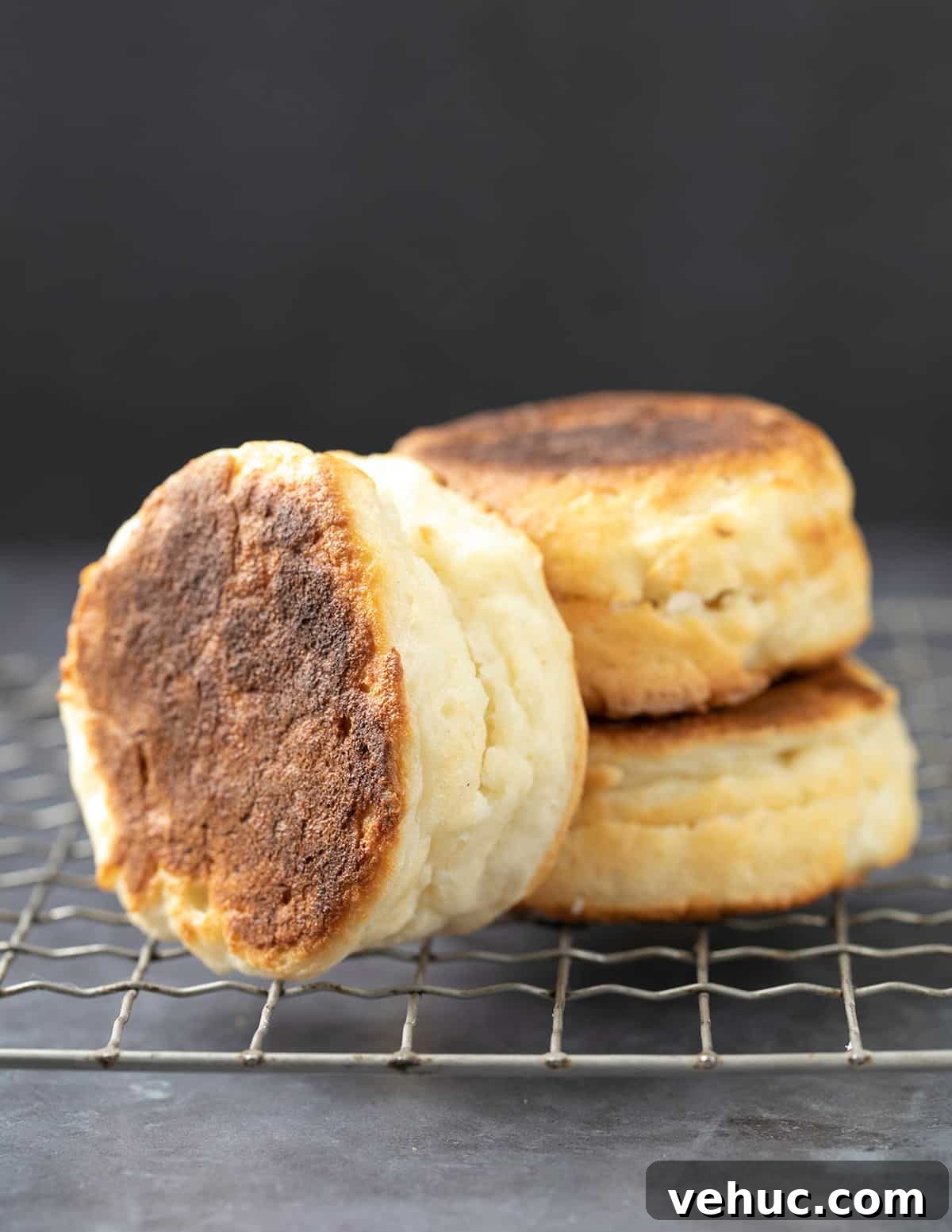 Stack of 2 English muffins with one more on its side all on a wire rack