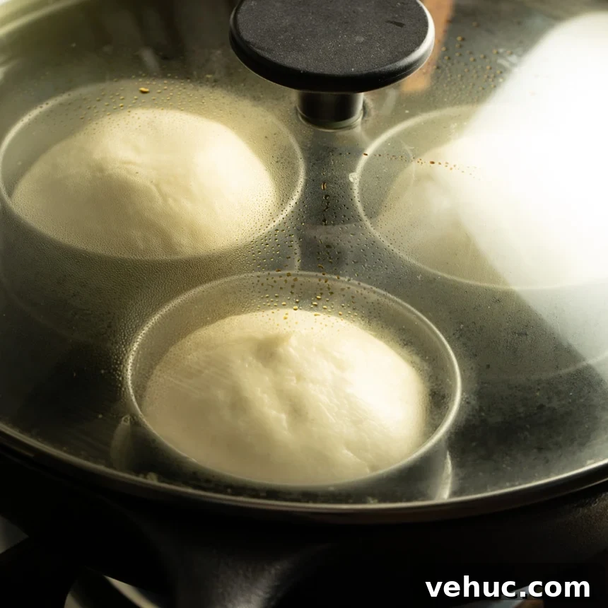 Risen dough portions visible through the glass lid of the skillet, showing steam and condensation inside.