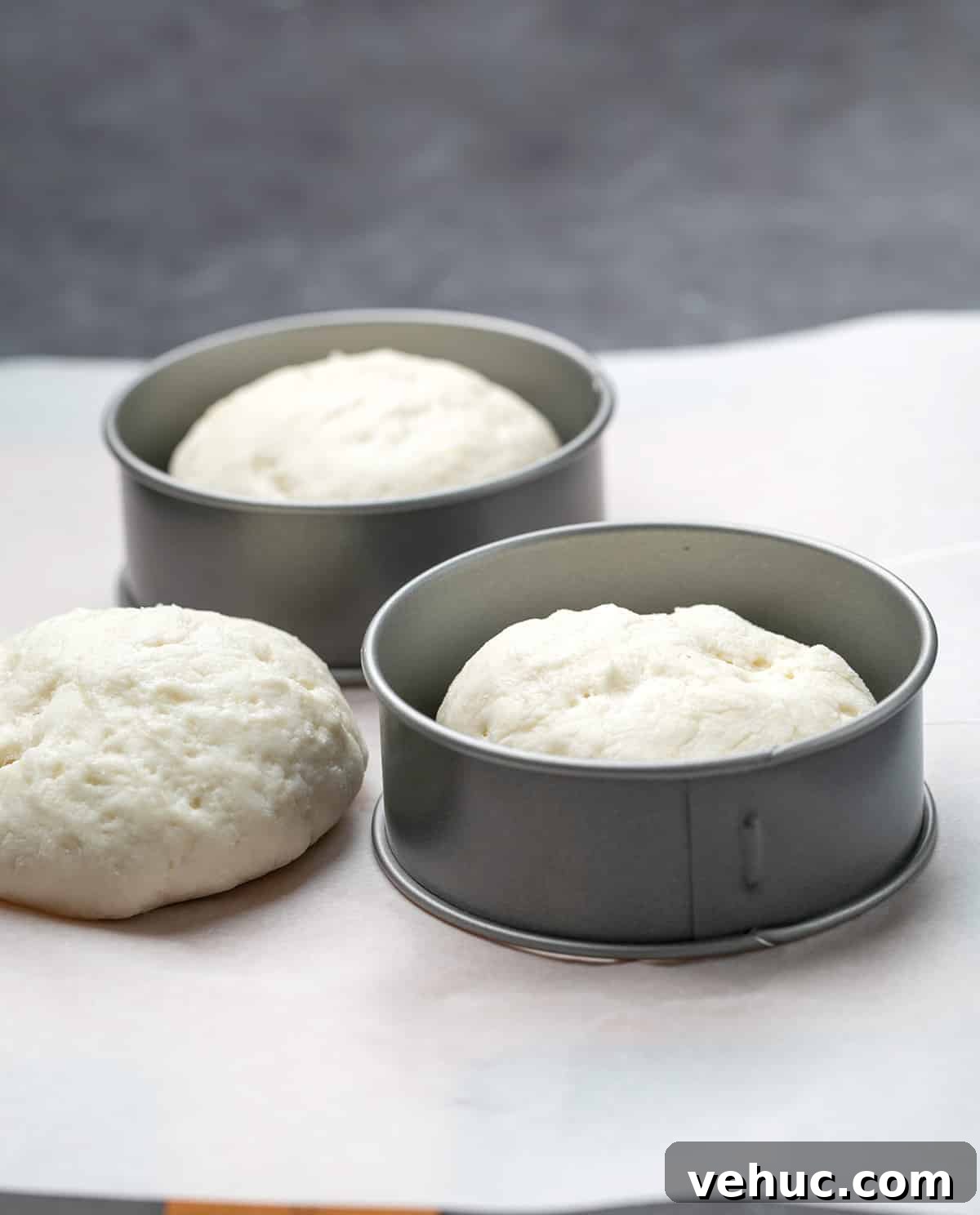 Three raw English muffins with 2 metal rings on white paper