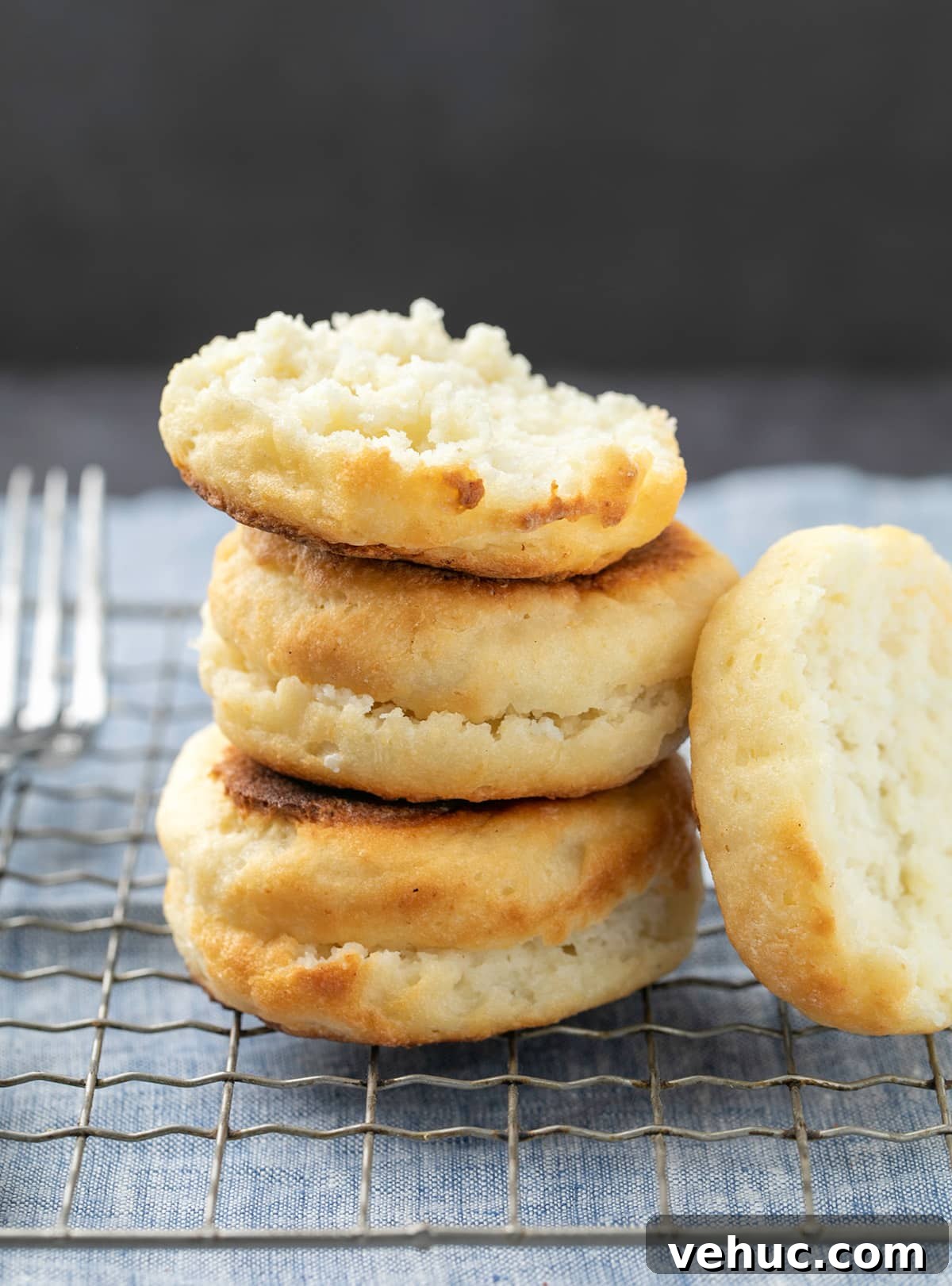 Stack of 2 full and one half English muffins with half propped on side on wire rack with fork