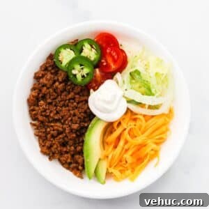 High-Protein Keto Taco Bowls for Low-Carb Meal Prep 13 High protein keto taco bowl with ground beef, shredded cheddar, avocado, cherry tomatoes, and jalapeños in a white bowl
