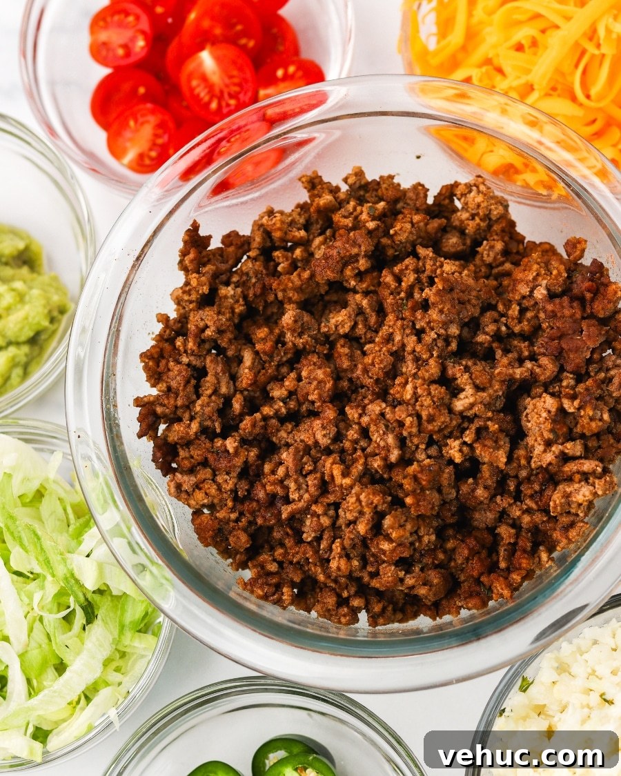 High-Protein Keto Taco Bowls for Low-Carb Meal Prep 7 All ingredients ready to be assembled for keto taco bowls including ground beef, lettuce, tomato, shredded cheddar cheese, cauliflower rice, guacamole, and sliced jalapenos