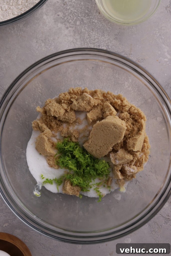 Brown sugar, granulated sugar and lime zest in a glass mixing bowl.