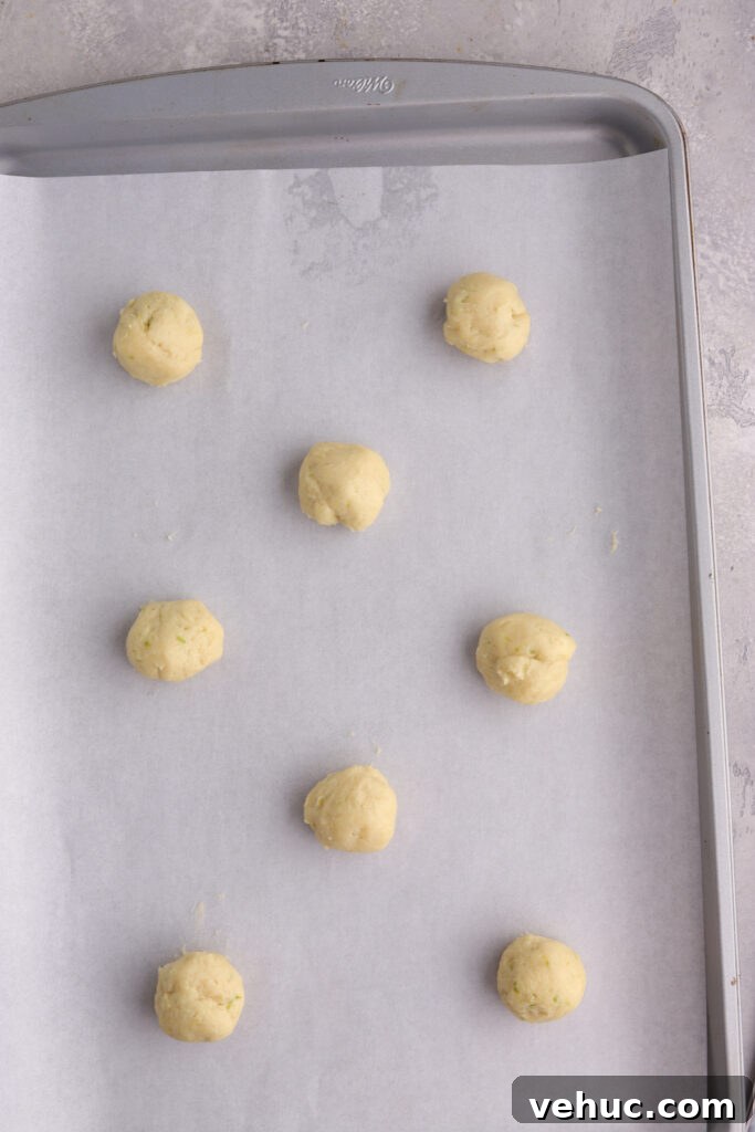 Cookie dough balls on a baking sheet lined with parchment paper.