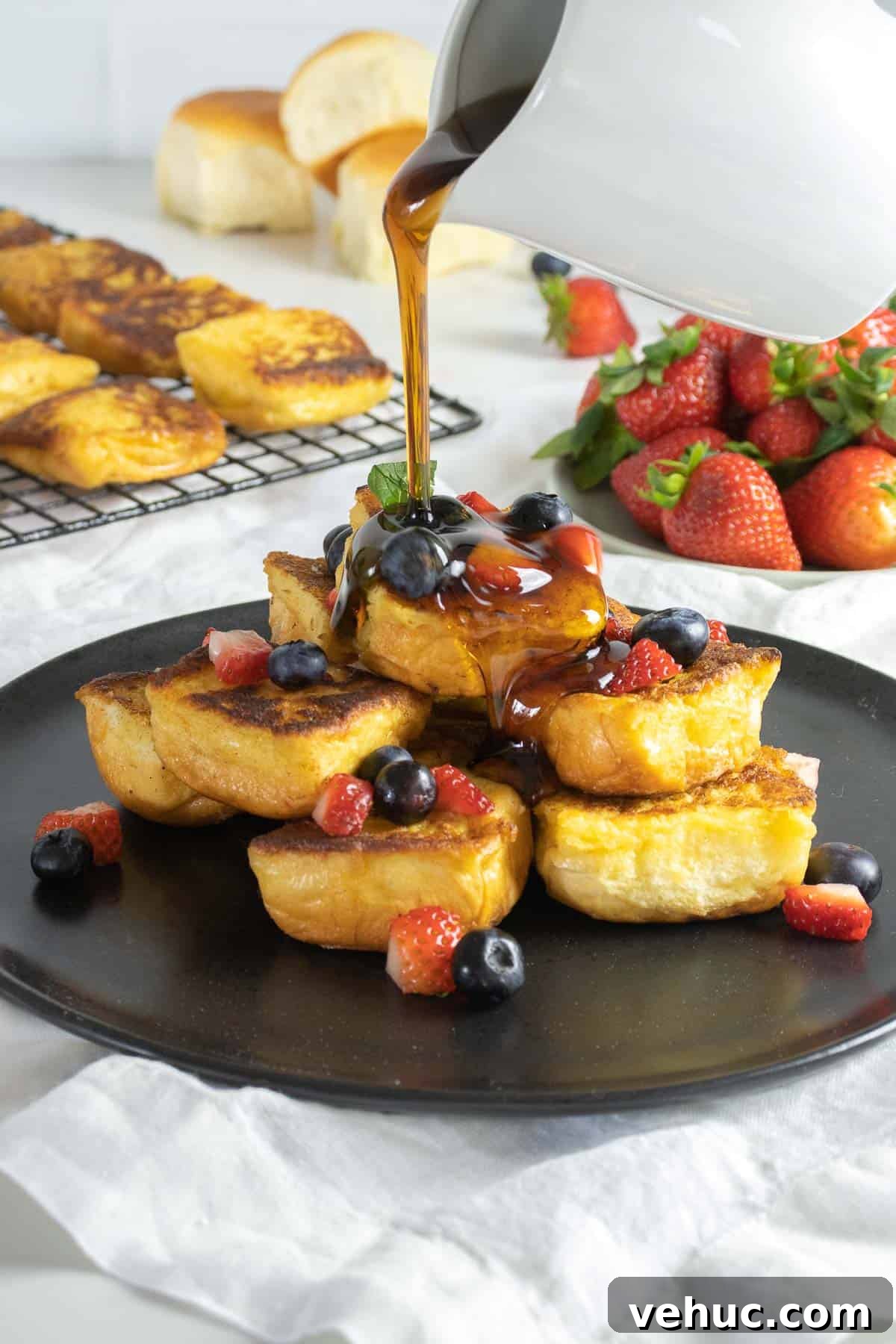 Hawaiian Roll French Toast Recipe with Pineapple Syrup 2 Hawaiian sweet bread French toast on a plate with berries and maple syrup.