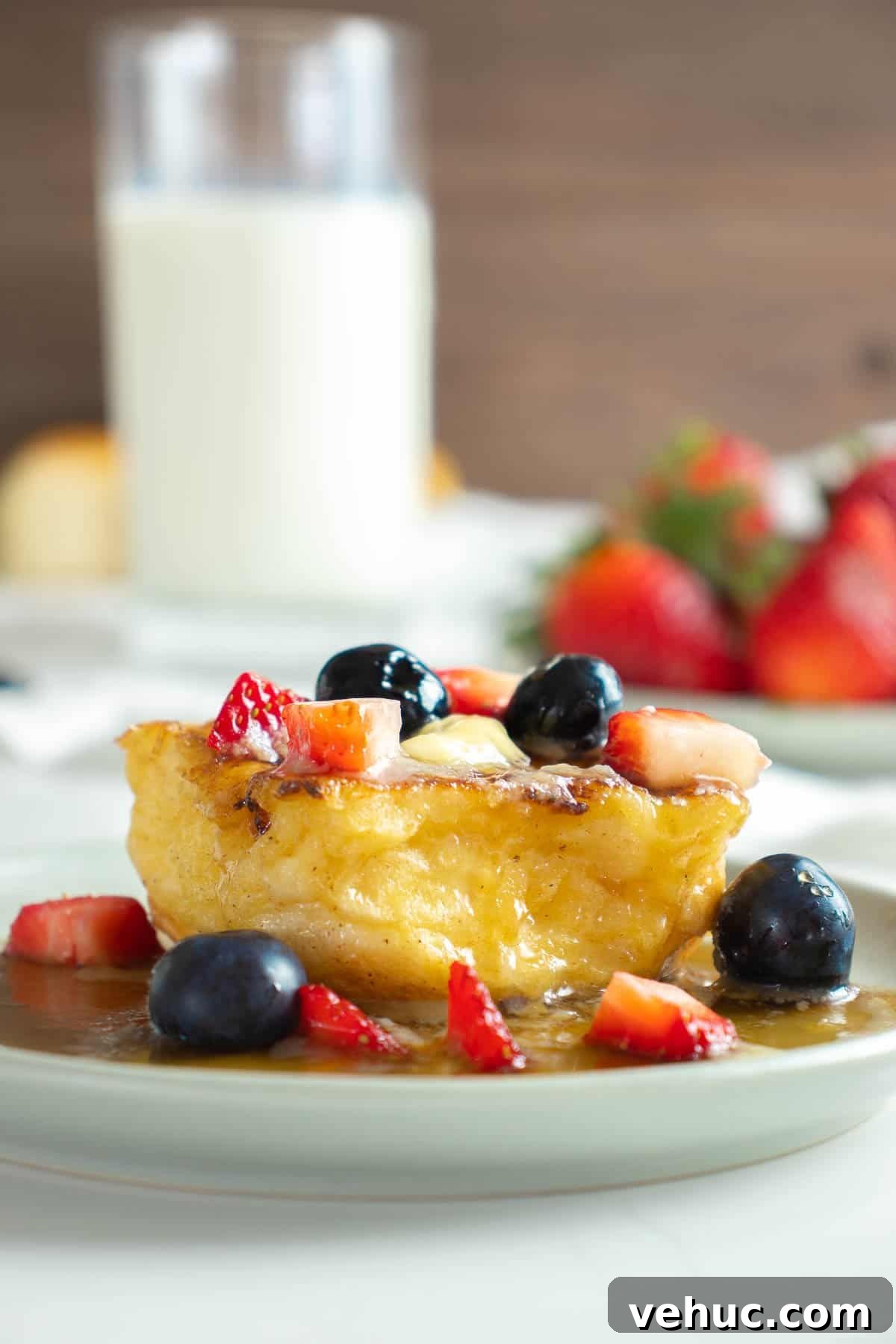 Hawaiian Roll French Toast Recipe with Pineapple Syrup 6 Close up of Hawaiian roll french toast on plate with butter, syrup and berries.