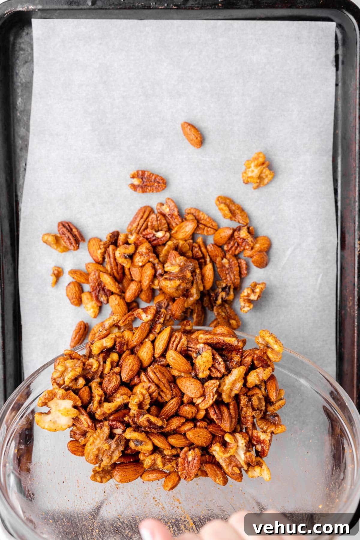 Cajun-Spiced Mixed Nuts: Bold and Flavorful Snack Recipe 5 overhead photo showing spicy nut mix being poured onto a parchment-lined baking sheet