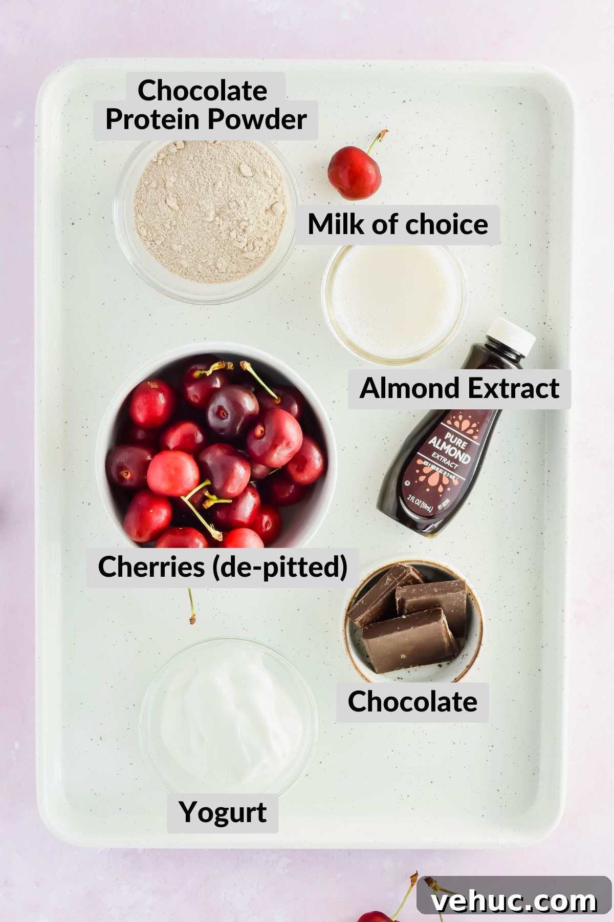 ingredients for chocolate cherry smoothie spread on white tray on light pink background.