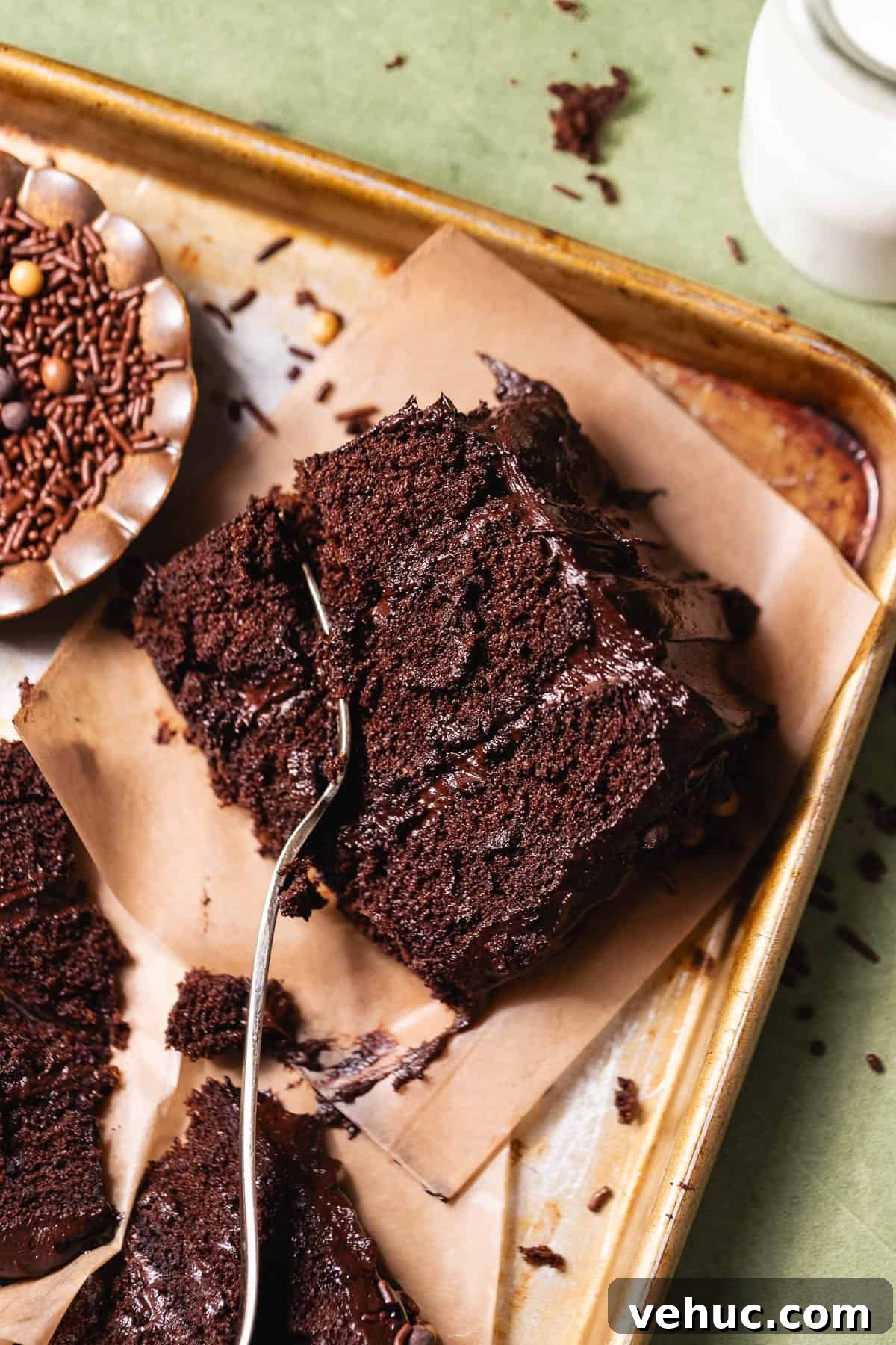 Moist Chocolate Cake Recipe That Tops Bakery Cakes 2 Piece of chocolate cake on parchment paper with a fork cutting into the moist crumb.