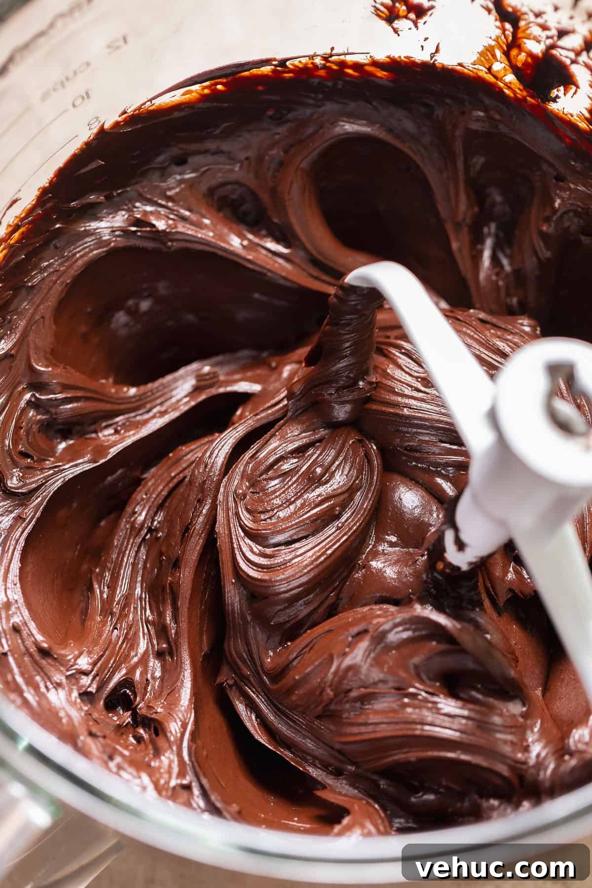Moist Chocolate Cake Recipe That Tops Bakery Cakes 6 Thick chocolate fudge frosting being mixed in a bowl with a paddle attachment.