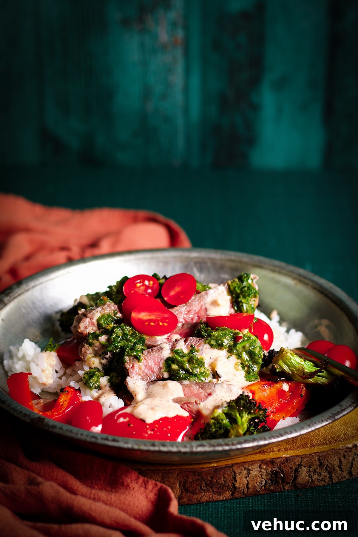 Garlic Aioli Steak & Rice Bowls with Fresh Chimichurri 2 A tin bowl filled with rice, roasted veggies, sliced steak, garlic aioli, chimichurri sauce, and cut cherry tomatoes.
