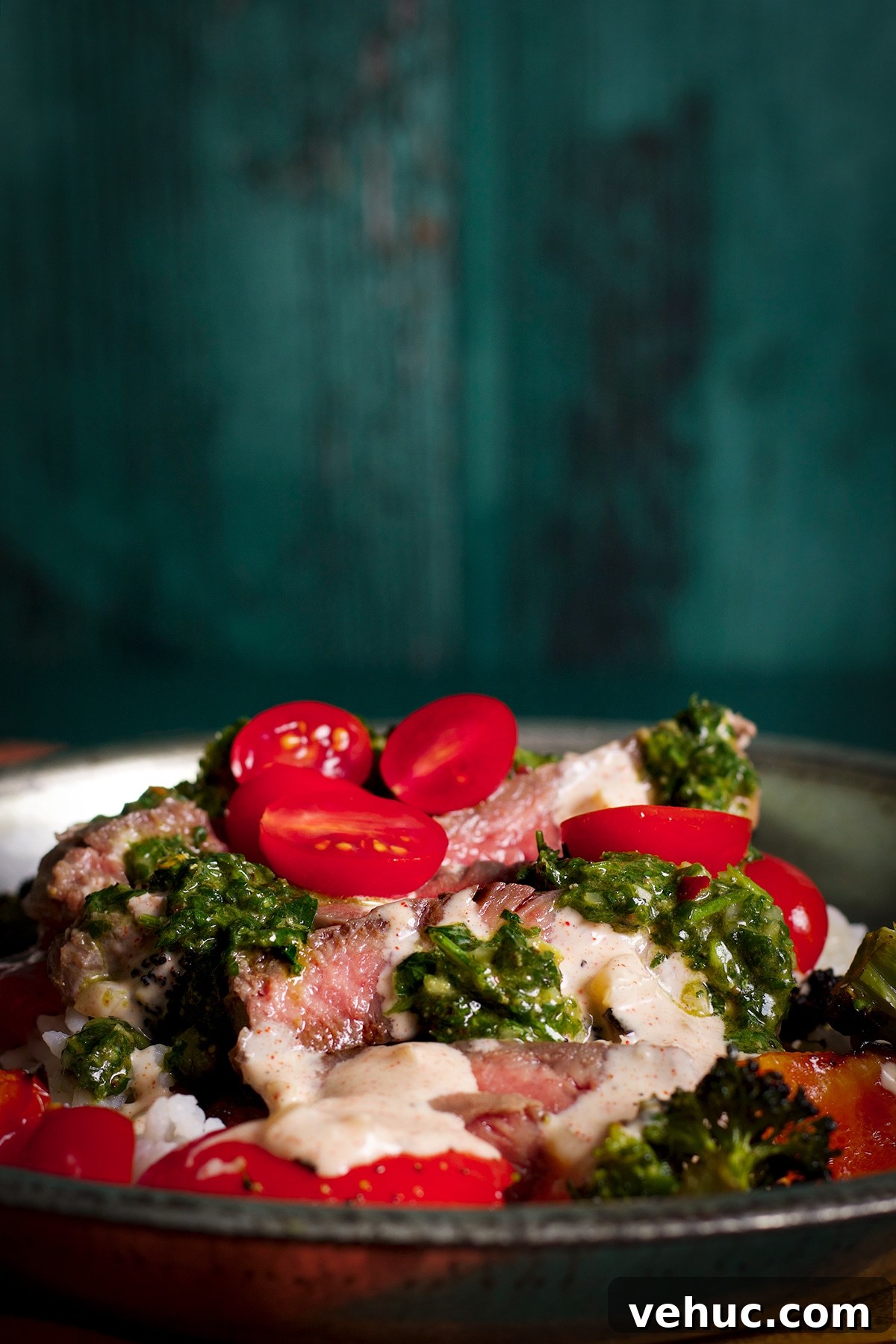 Garlic Aioli Steak & Rice Bowls with Fresh Chimichurri 3 A tin bowl filled with rice, roasted veggies, sliced steak, garlic aioli, chimichurri sauce, and cut cherry tomatoes.