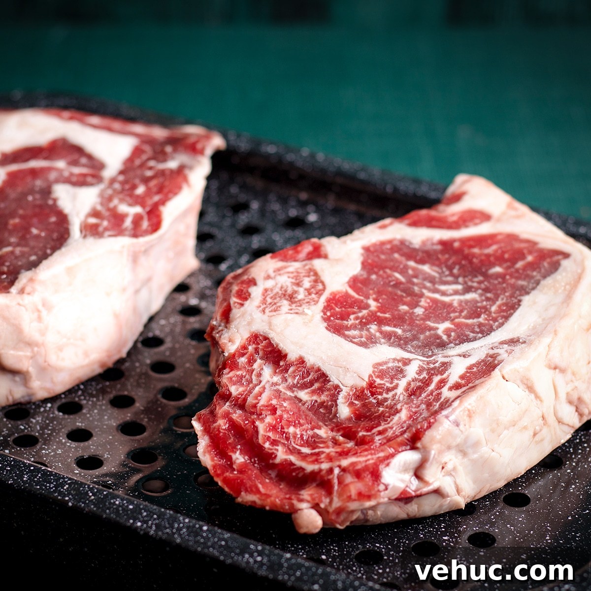 Garlic Aioli Steak & Rice Bowls with Fresh Chimichurri 5 Two rib-eye steaks on a broiler pan, ready to go in the oven.