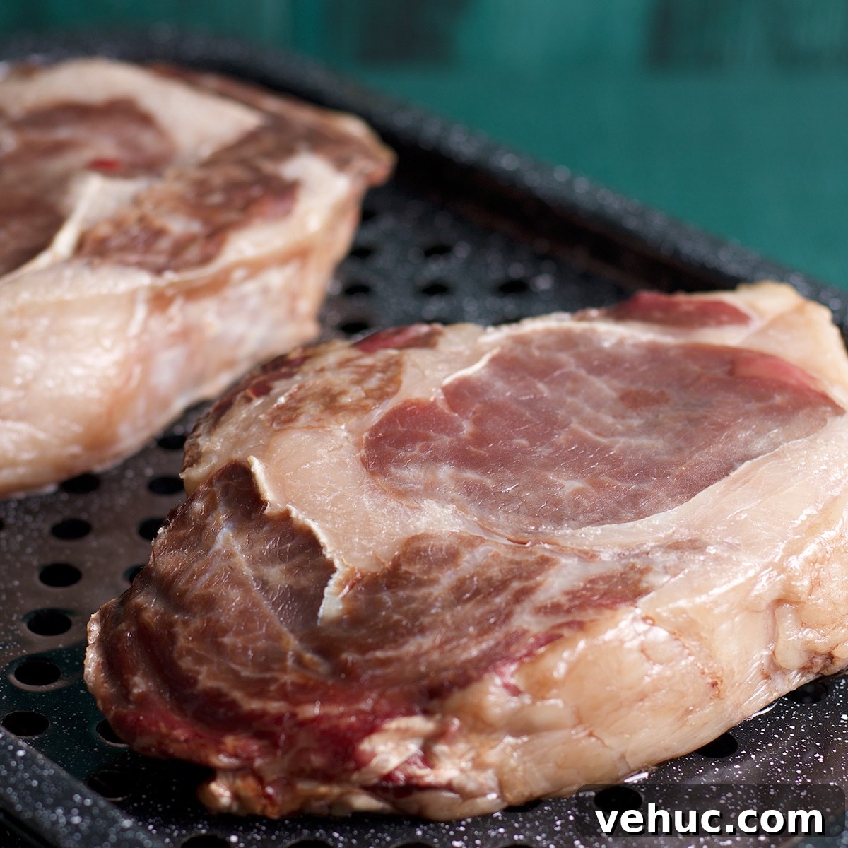 Garlic Aioli Steak & Rice Bowls with Fresh Chimichurri 7 Two ribeye steaks on a broiler pan that have been partially cooked in the oven and are now ready to be seared.