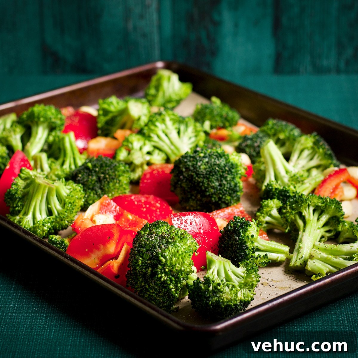 Garlic Aioli Steak & Rice Bowls with Fresh Chimichurri 9 Broccoli florets and chunks of red bell pepper spread out on a parchment lined rimed baking sheet.