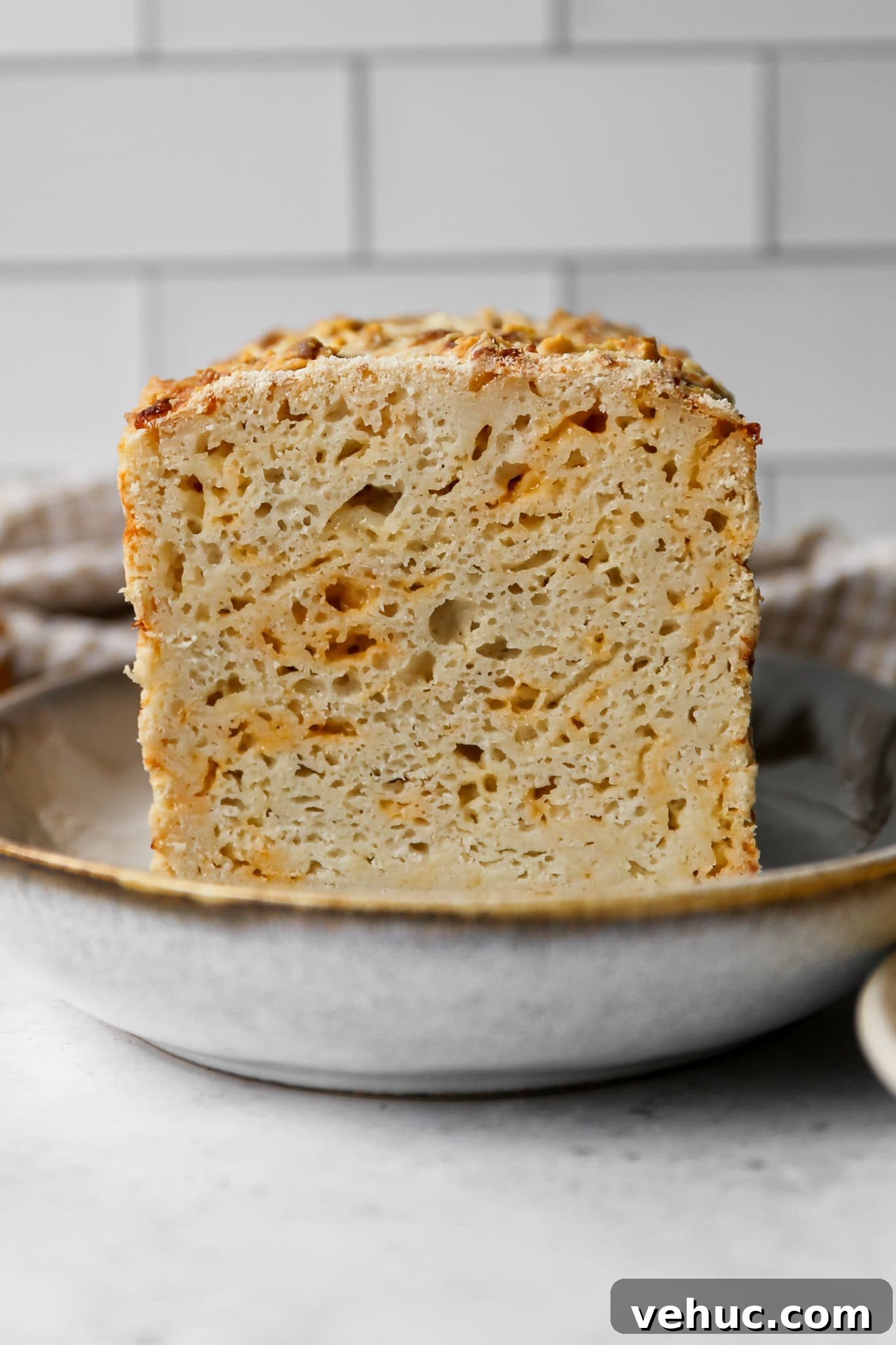 Gluten-Free Cheesy Sourdough Bread Recipe for Crispy Crust 3 a loaf of gluten free cheesy sourdough bread with a slice cut from it sitting on a platter