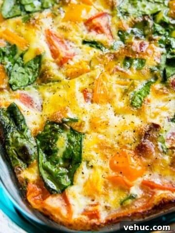 A glass dish filled with a bacon and vegetable egg casserole.