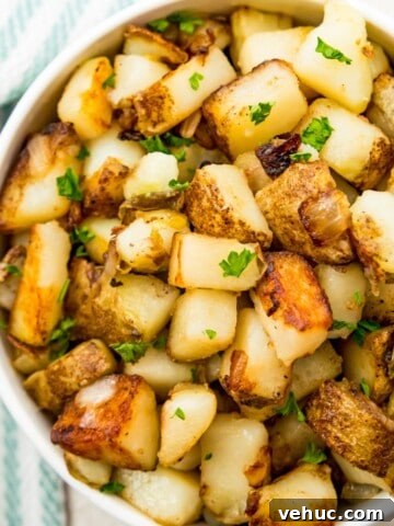 A bowl of southern fried potatoes and onions topped with fresh parsley.