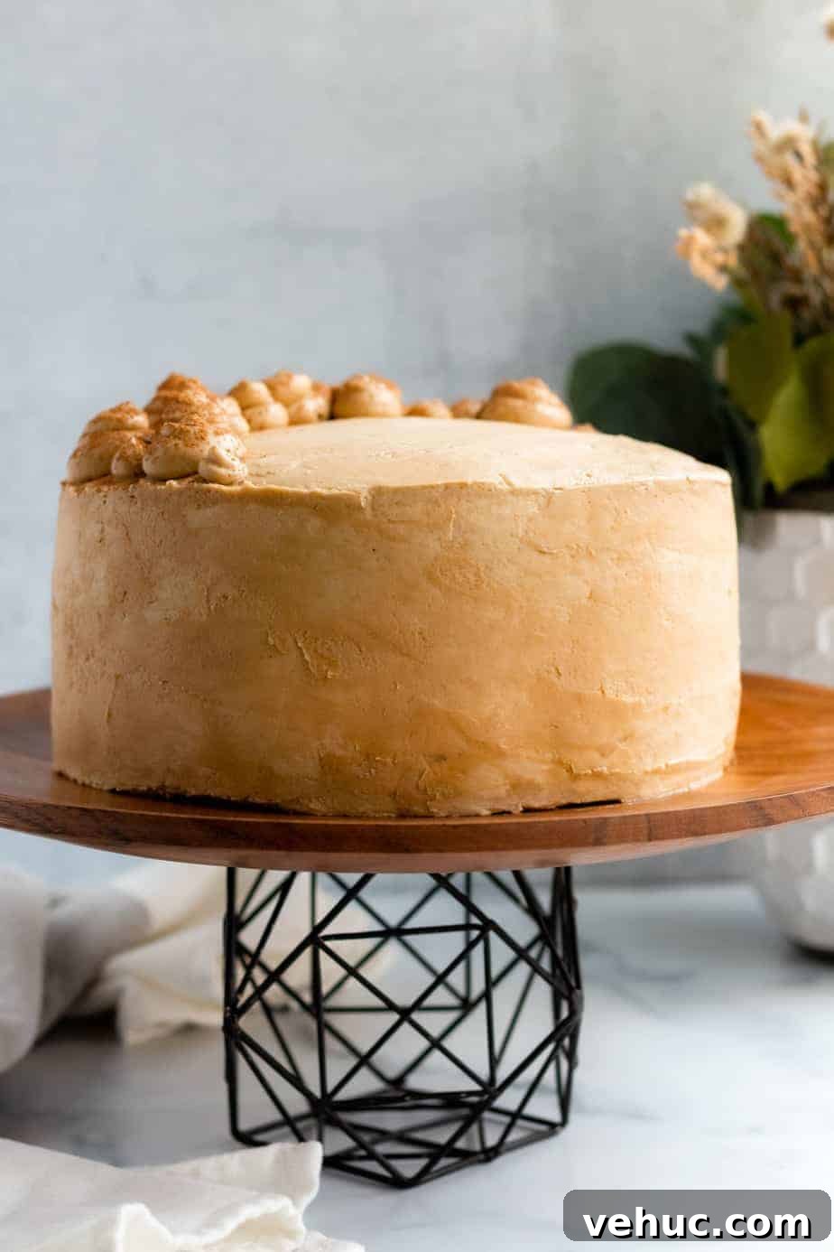 Decadent Chocolate Mocha Cake Recipe with Espresso Frosting 9 chocolate mocha cake on a wood and black metal cake stand with a white vase of flowers