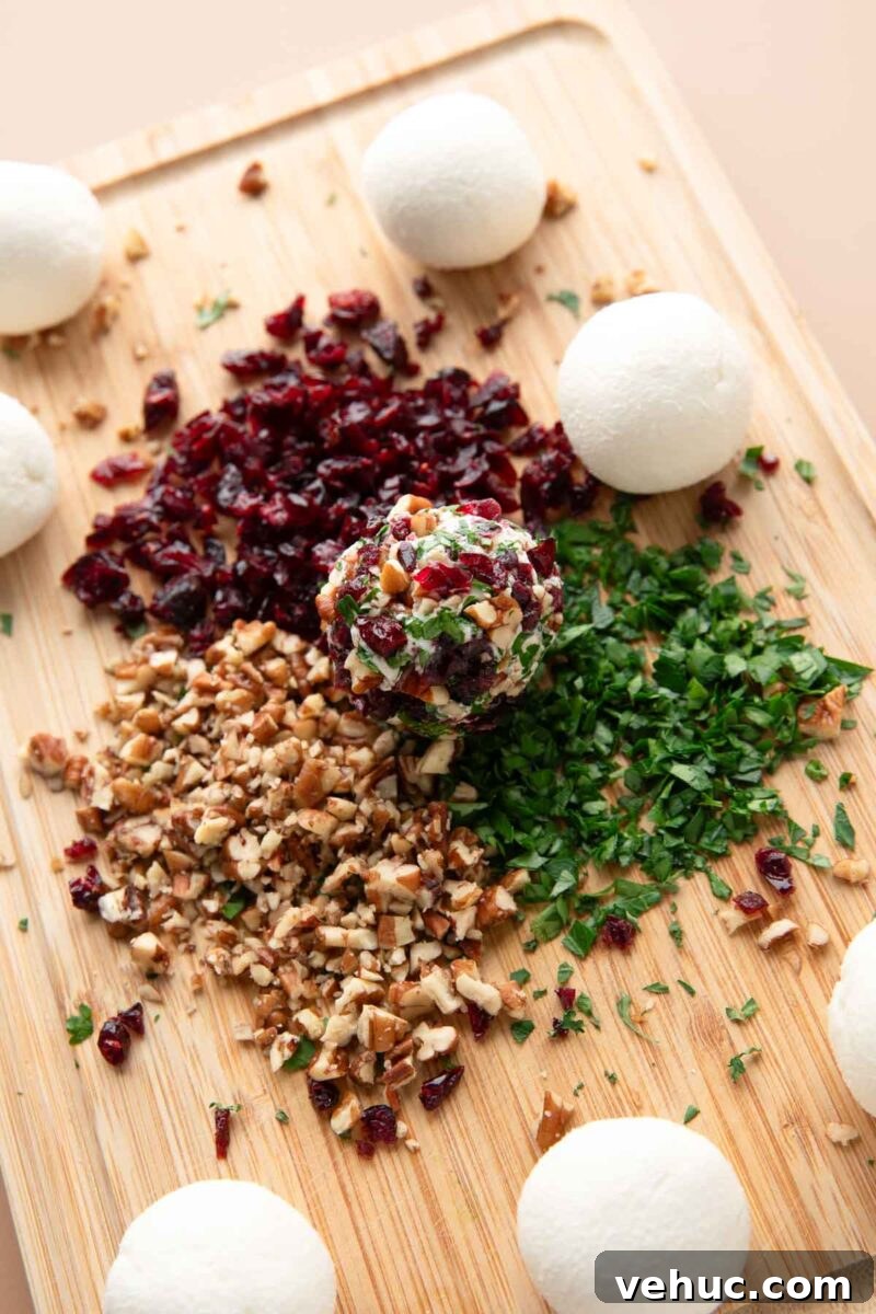Candied Pecan Cranberry Goat Cheese Bites for Holiday Appetizers 7 goat cheese balls rolled in nuts, herbs, and dried cranberries on a cutting board