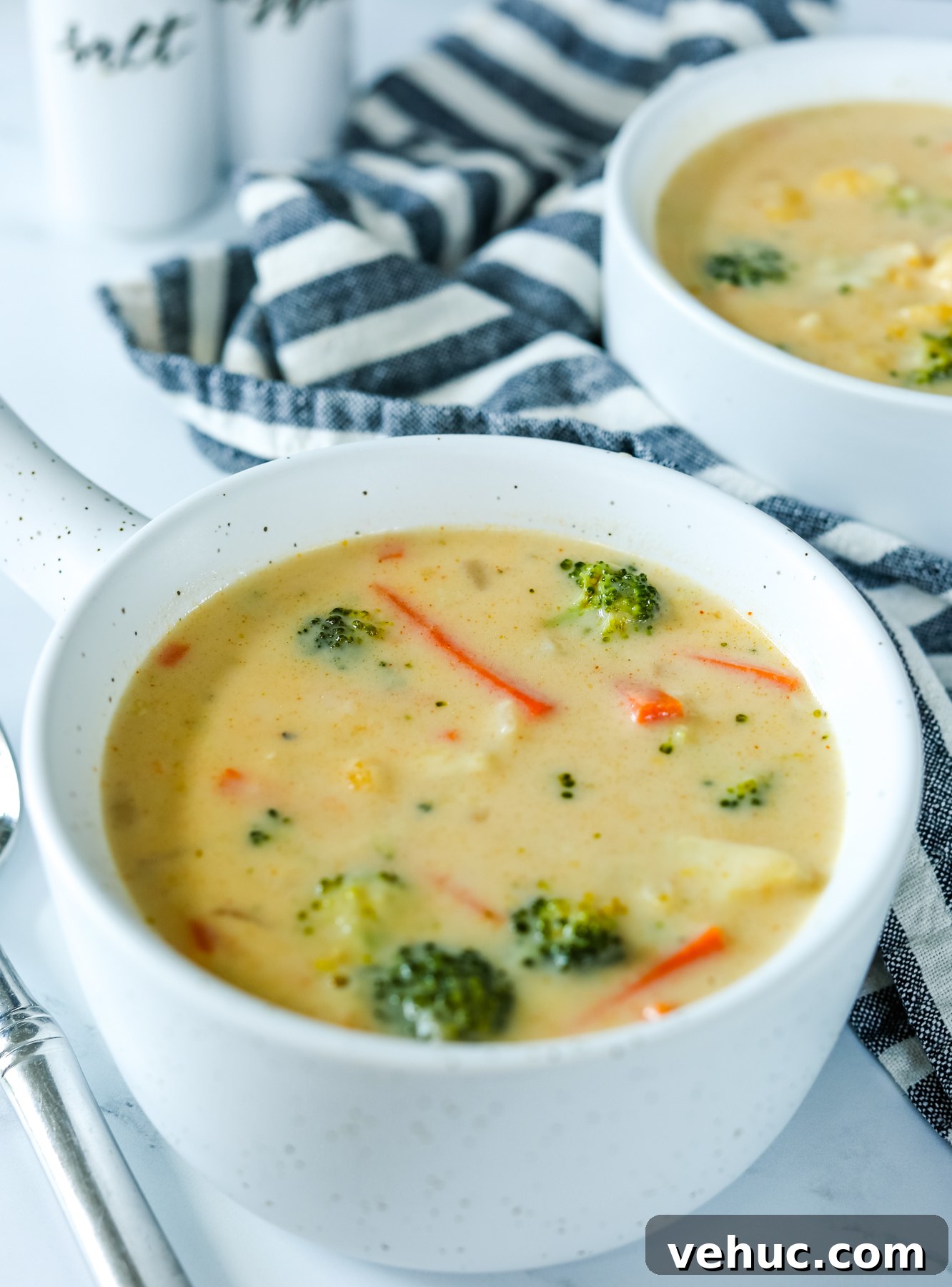 Creamy Broccoli and Cauliflower Soup Recipe for Comfort Meals 4 a bowl of broccoli cauliflower soup with a striped napkin and second bowl in the background