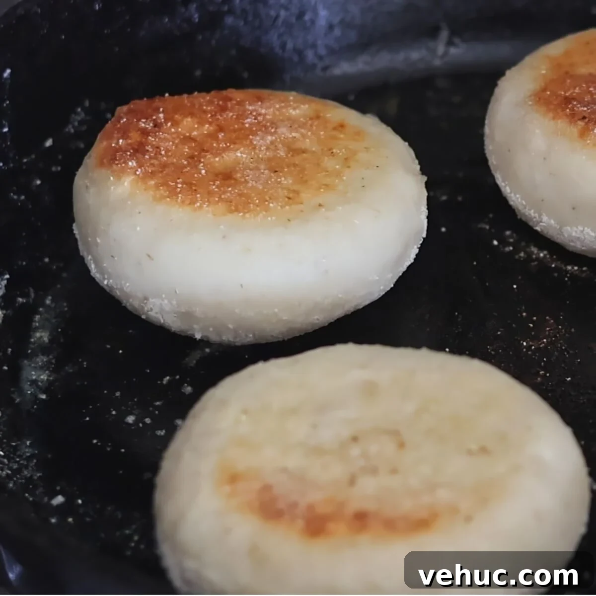 Gluten-Free Sourdough English Muffins Recipe You’ll Love 14 muffins in cast iron skillet browned on one side.