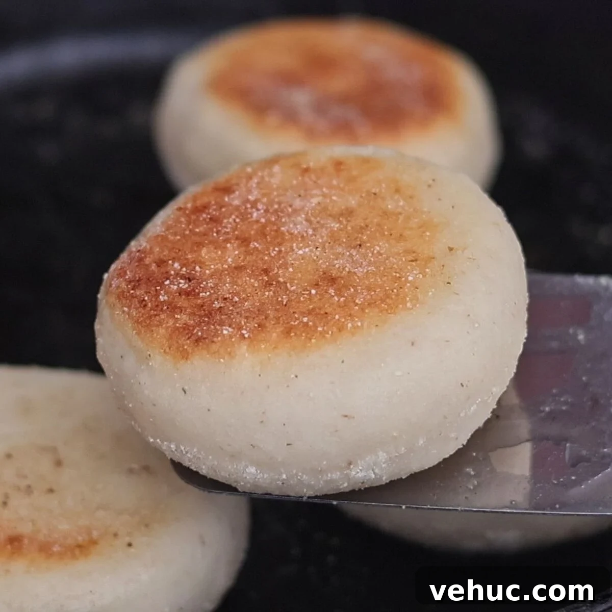 Gluten-Free Sourdough English Muffins Recipe You’ll Love 16 up close shot of one golden brown muffin on stainless steel spatula.
