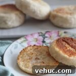 Gluten-Free Sourdough English Muffins Recipe You’ll Love 18 split english muffin on flowered plate with whole english muffins in the background.