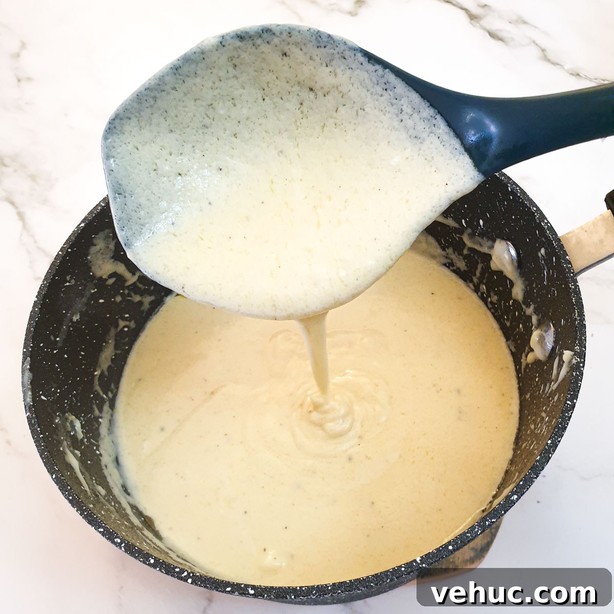 Ultimate Creamy Macaroni & Cheese Recipe for Comfort Night 8 Cheese sauce being poured from a large spoon into a saucepan, showing the consistency.