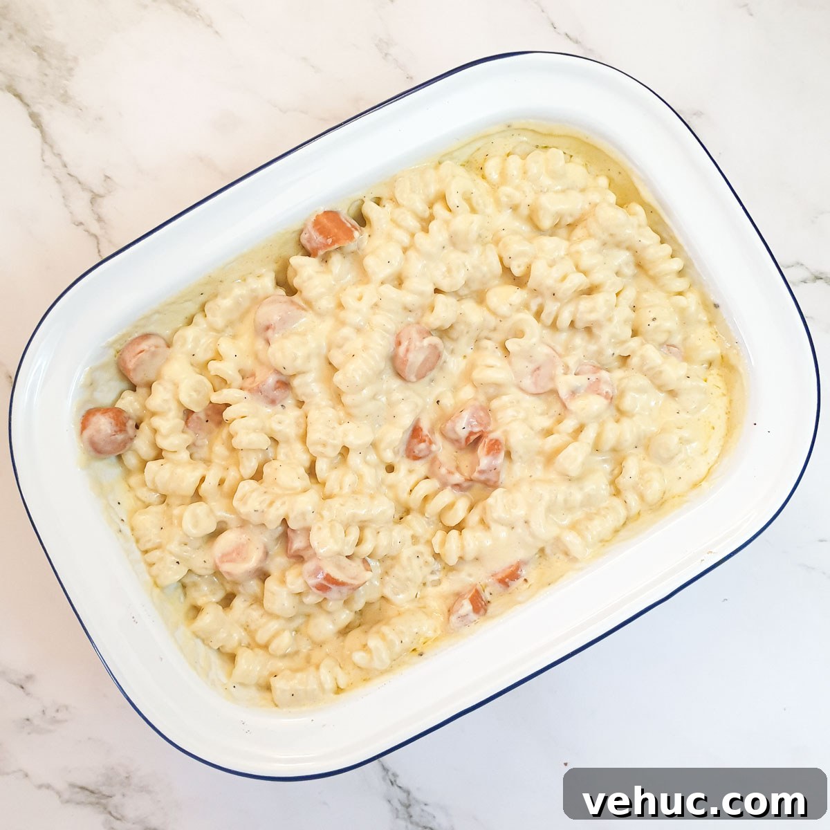 Ultimate Creamy Macaroni & Cheese Recipe for Comfort Night 10 Pasta and sausages in a baking dish mixed with cheese sauce.