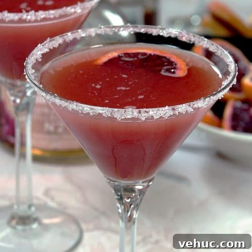 Blood Orange Cosmopolitan Cocktail Recipe — Bright Citrus Martini 7 A single Blood Orange Cosmopolitan cocktail with a sugar rim and slice of blood orange garnish.