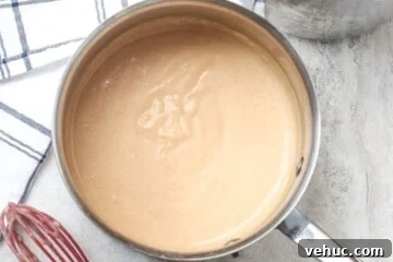Classic Homemade Cream of Chicken Soup Recipe for Comforting Meals 4 Creamy homemade cream of chicken soup in saucepan next to red whisk.