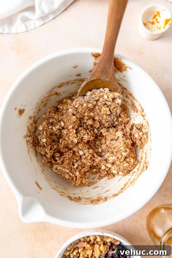 Cranberry Orange Oatmeal Cookies (Vegan Recipe) 5 Oatmeal cookie dough in mixing bowl with a wooden spoon.