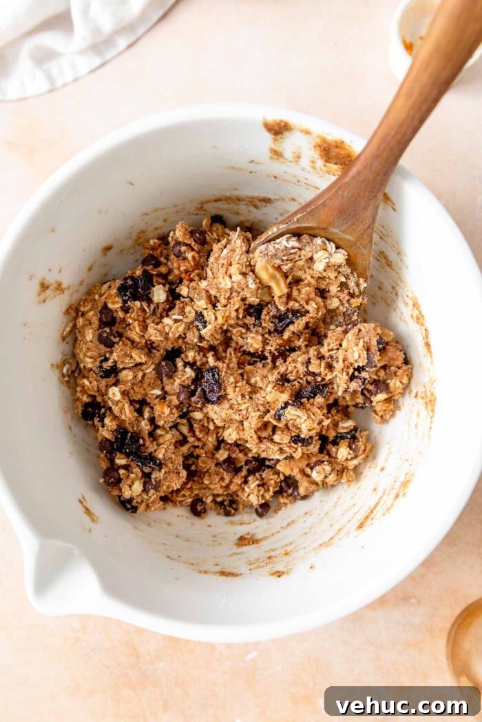 Cranberry Orange Oatmeal Cookies (Vegan Recipe) 6 Cranberry orange oatmeal cookie dough in a mixing bowl with a wooden spoon.