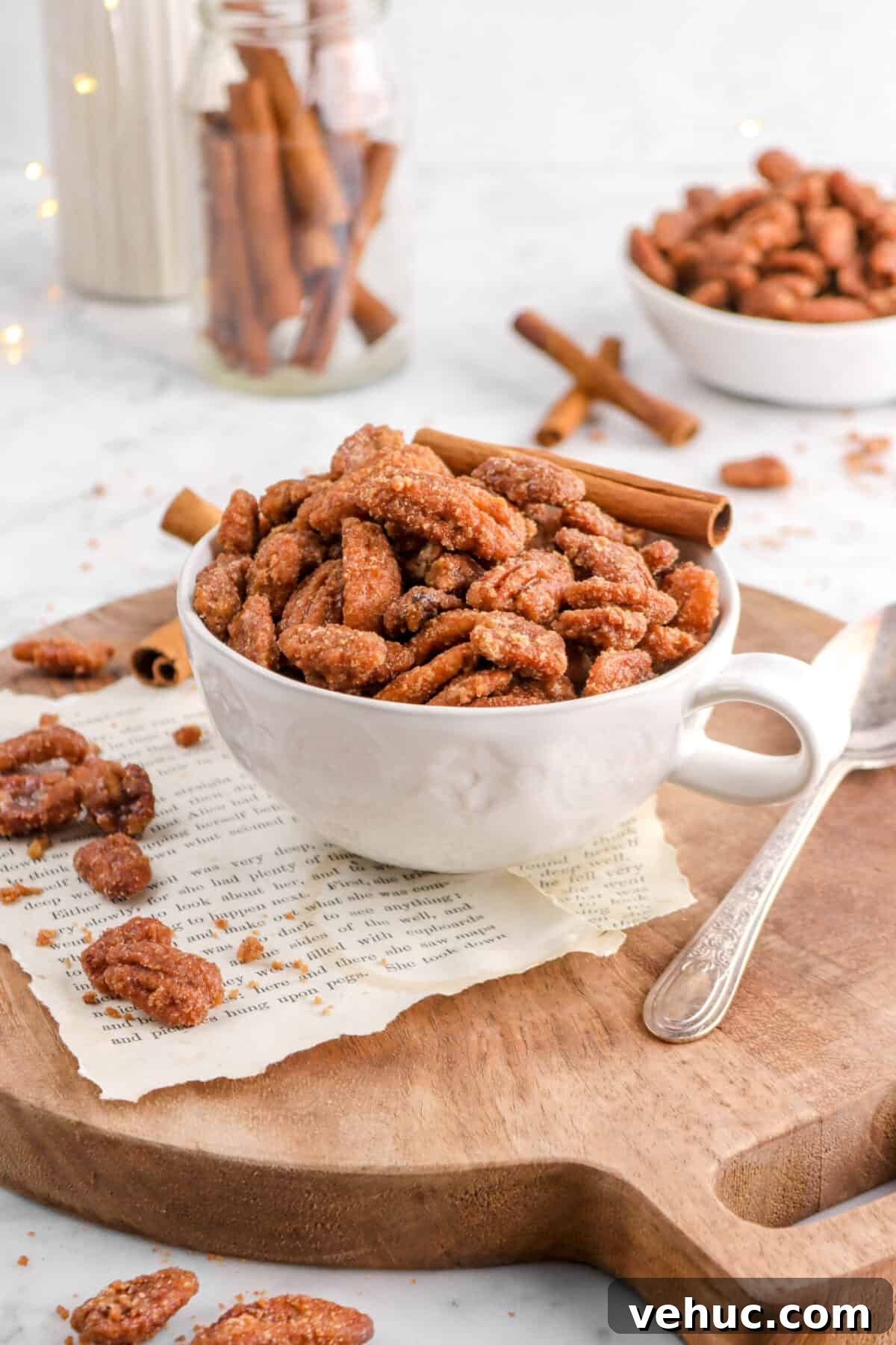 Top 21 Most-Loved Recipes of 2021: Trending Dishes You’ll Want to Try 12 candied pecans in white mug with fairy lights, cinnamon sticks, and more pecans scattered around