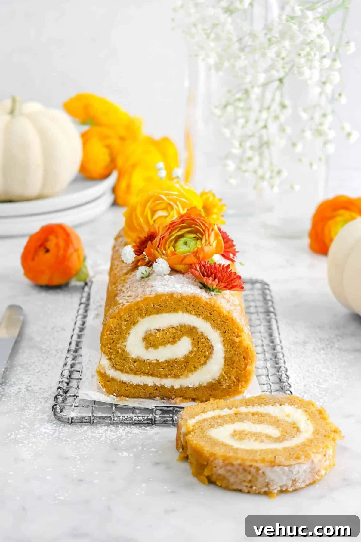 Top 21 Most-Loved Recipes of 2021: Trending Dishes You’ll Want to Try 16 pumpkin roll on wire rack with small piece of parchment, flowers, on top, more flowers around, and two white pumpkins