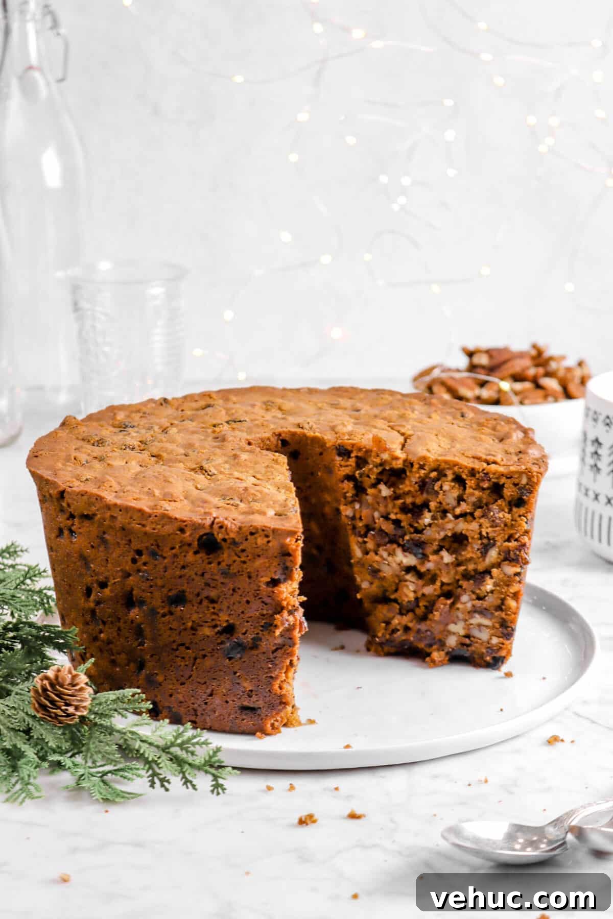 Top 21 Most-Loved Recipes of 2021: Trending Dishes You’ll Want to Try 19 nut cake with a slice taken out of it on a white plate with fairy lights, greenery, and glasses