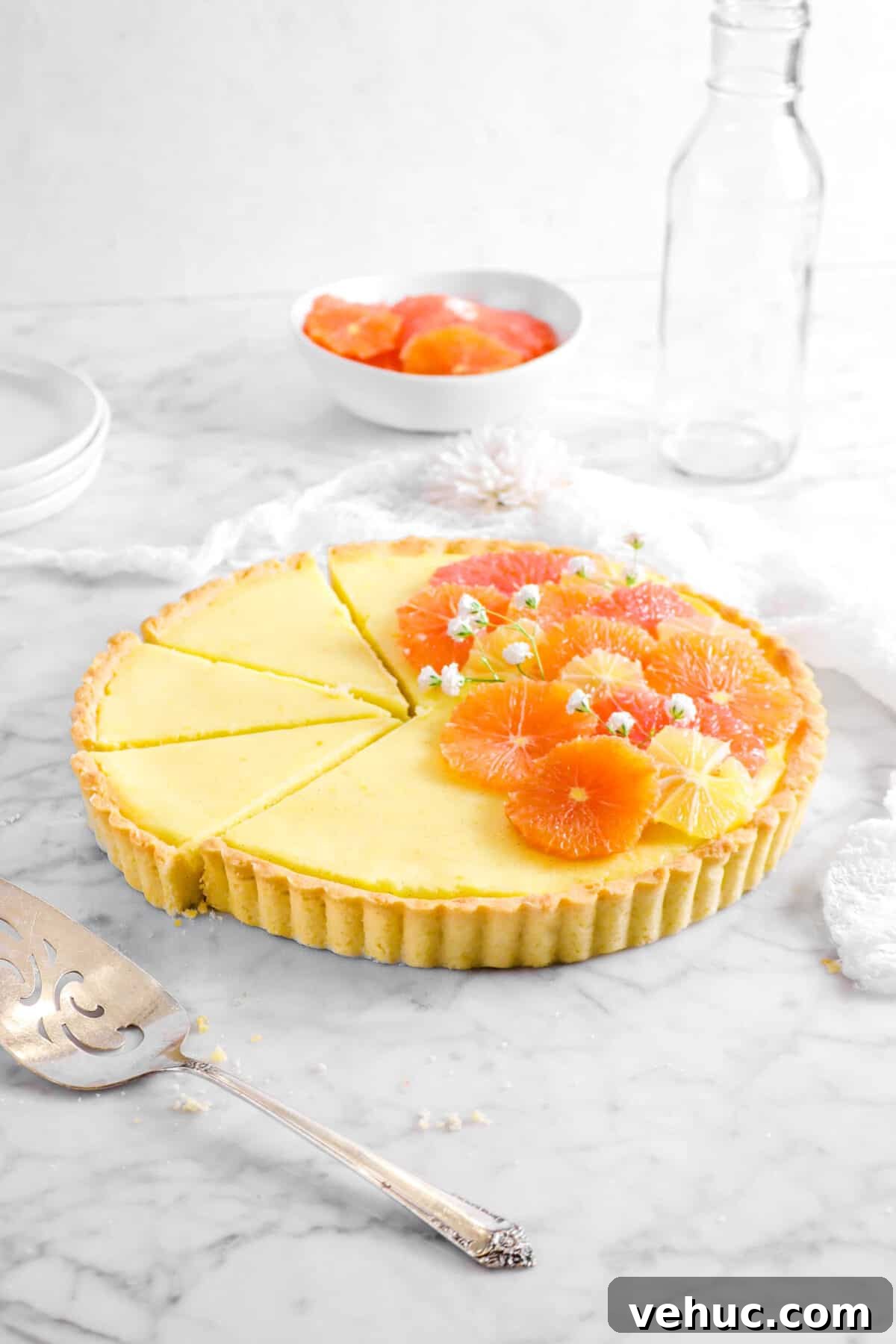 Top 21 Most-Loved Recipes of 2021: Trending Dishes You’ll Want to Try 24 citrus tart with three slices laying next to it, a cake knife, white napkin, glass, and bowl of citrus slices