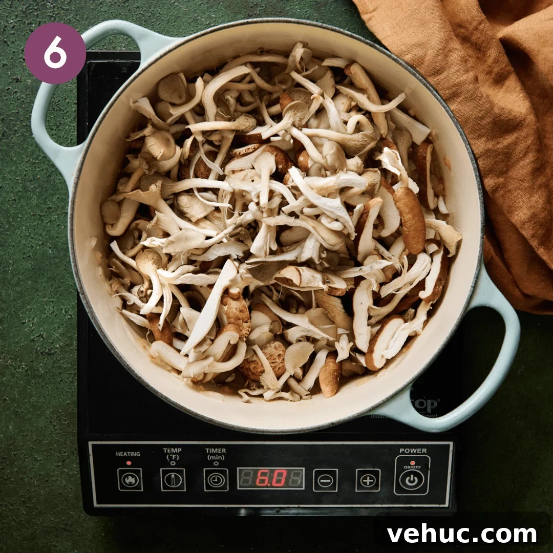 Velvety Vegan Mushroom Soup Recipe for Cozy Weeknights 11 a big pile of sliced and torn mushrooms sitting in a light blue dutch oven.