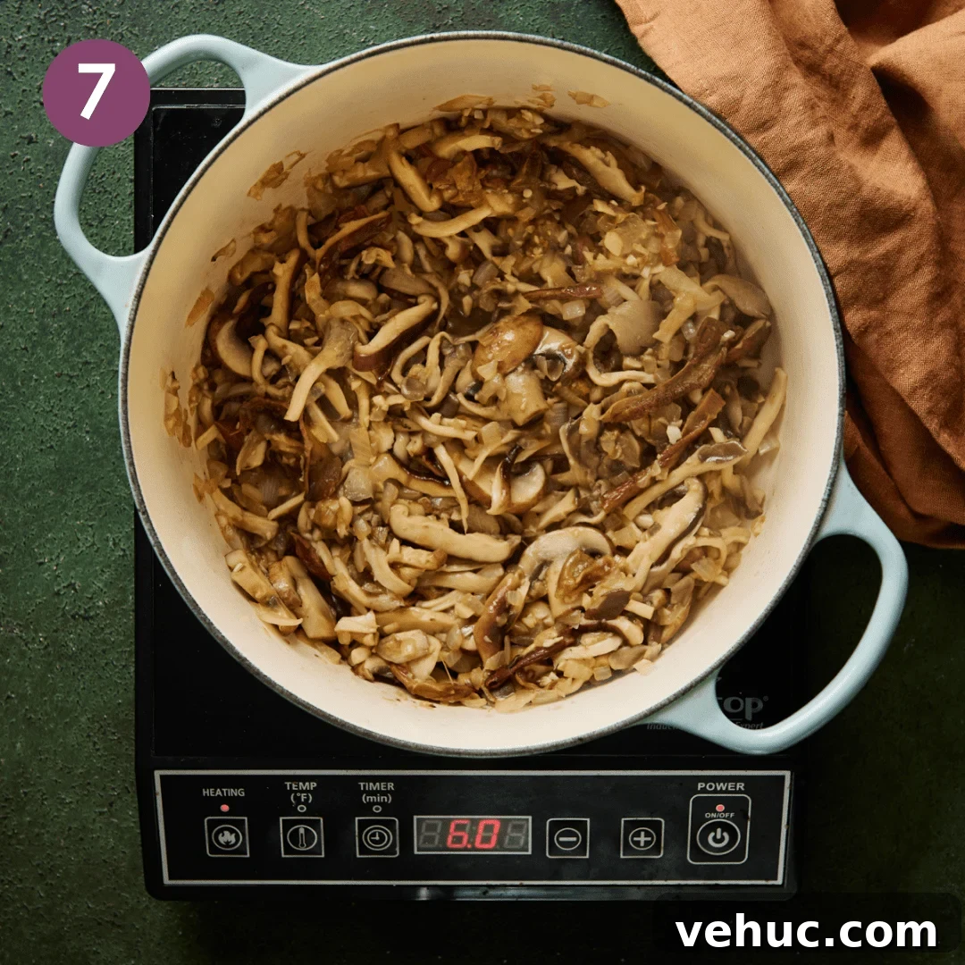 Velvety Vegan Mushroom Soup Recipe for Cozy Weeknights 12 sliced mushrooms sautéing in a light blue dutch oven.