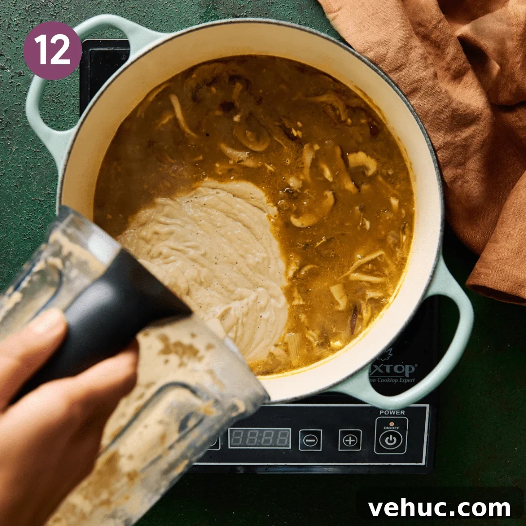 Velvety Vegan Mushroom Soup Recipe for Cozy Weeknights 15 woman's hands pouring blended mushroom soup in a soup pot of mushroom soup.