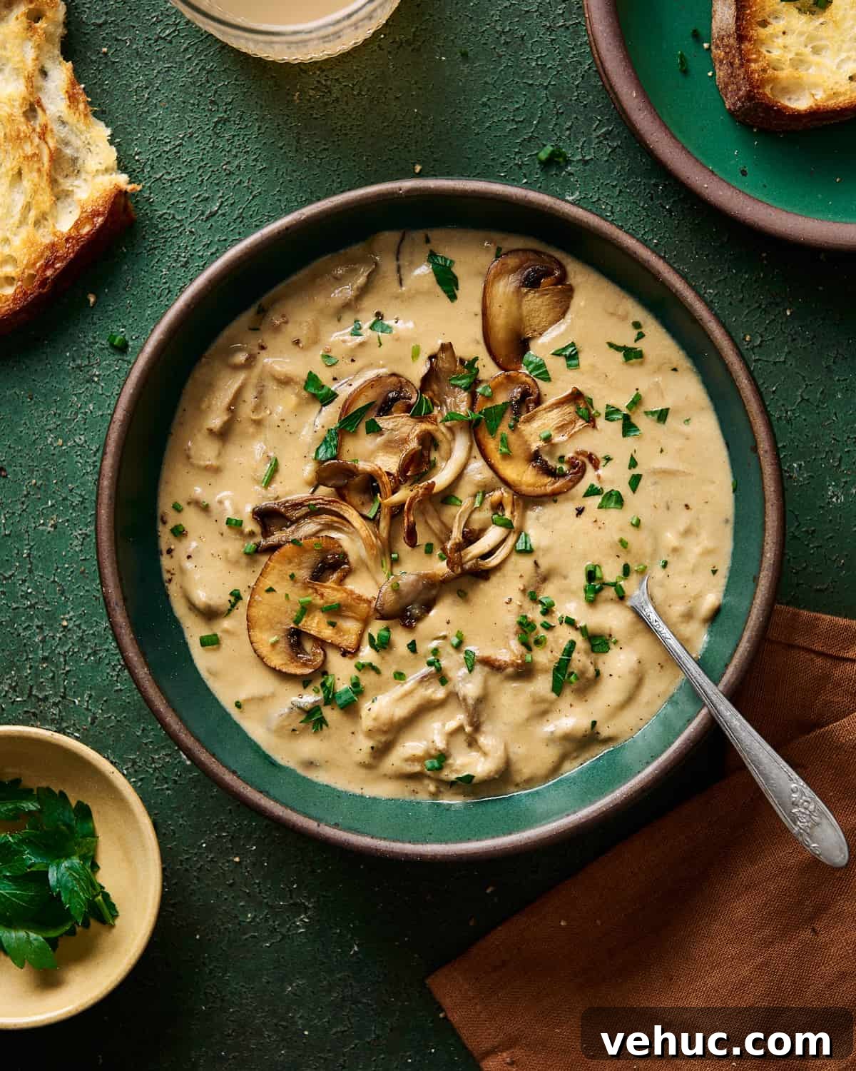 Velvety Vegan Mushroom Soup Recipe for Cozy Weeknights 18 creamy vegan mushroom soup with seared mushrooms on top in a green ceramic bowl on a green table.