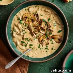 Velvety Vegan Mushroom Soup Recipe for Cozy Weeknights 20 creamy vegan mushroom soup with seared mushrooms on top in a green ceramic bowl on a green table.