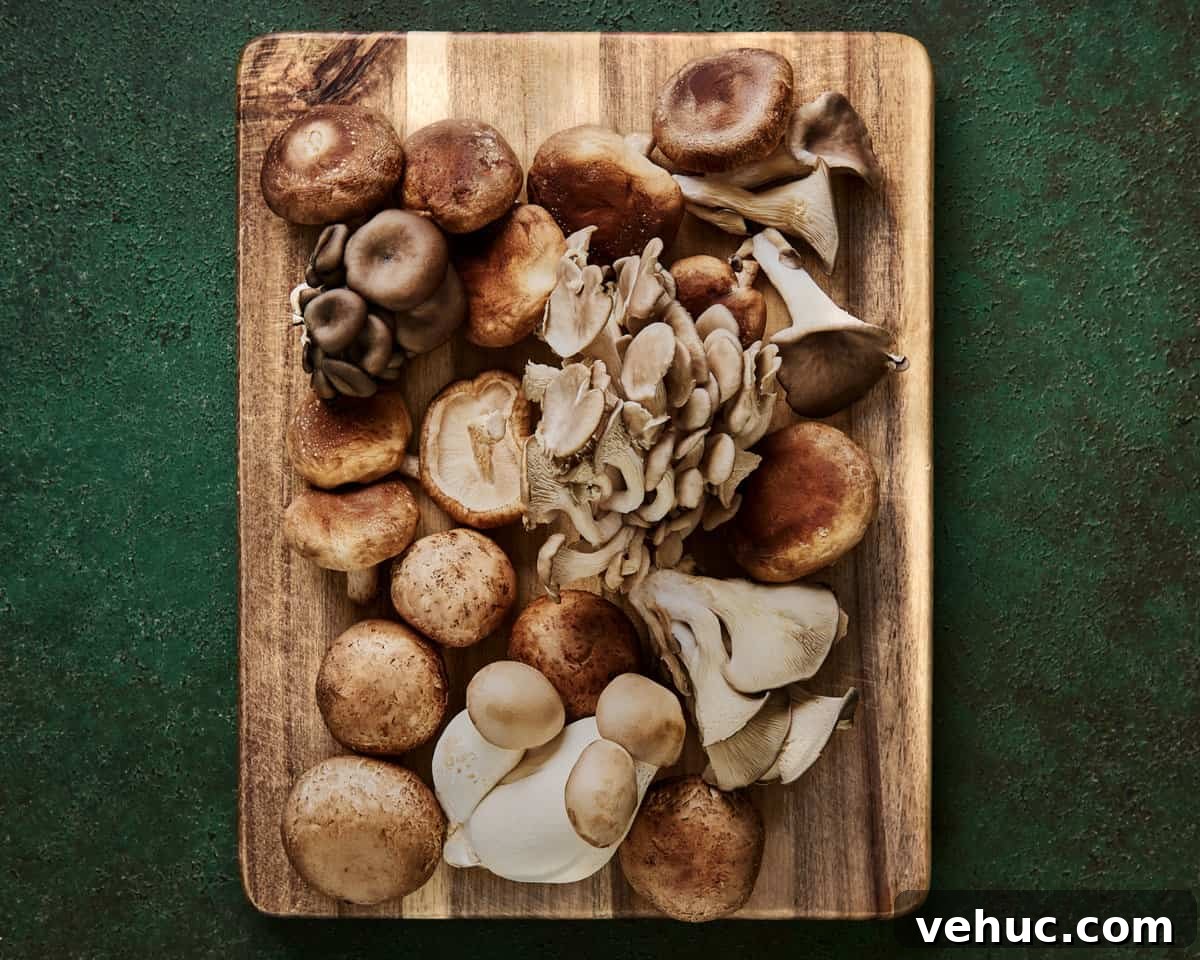 Velvety Vegan Mushroom Soup Recipe for Cozy Weeknights 5 a variety of beautiful whole mushrooms on a wooden cutting board on a green surface.