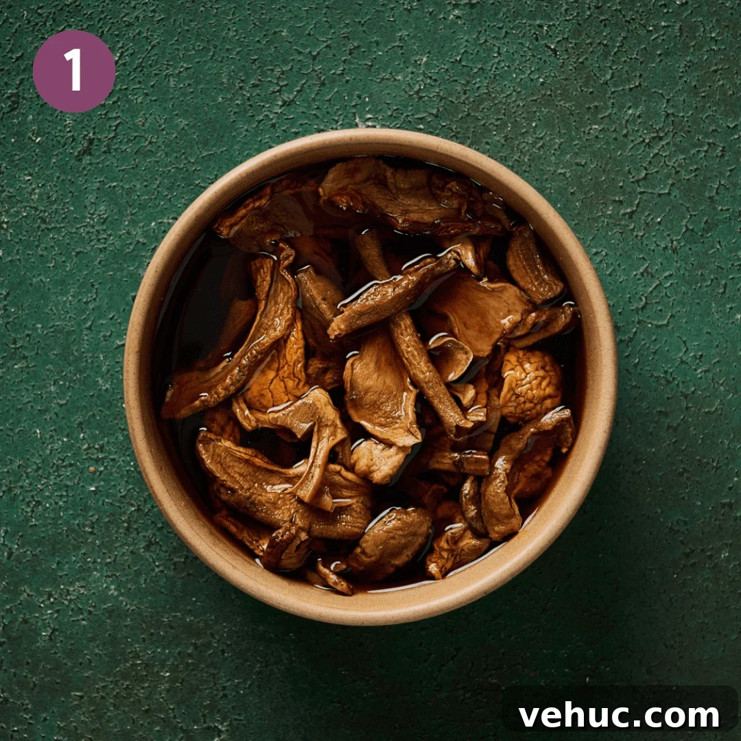 Velvety Vegan Mushroom Soup Recipe for Cozy Weeknights 6 a tan bowl of dried mushrooms rehydrating in liquid for mushroom stock on a green surface.