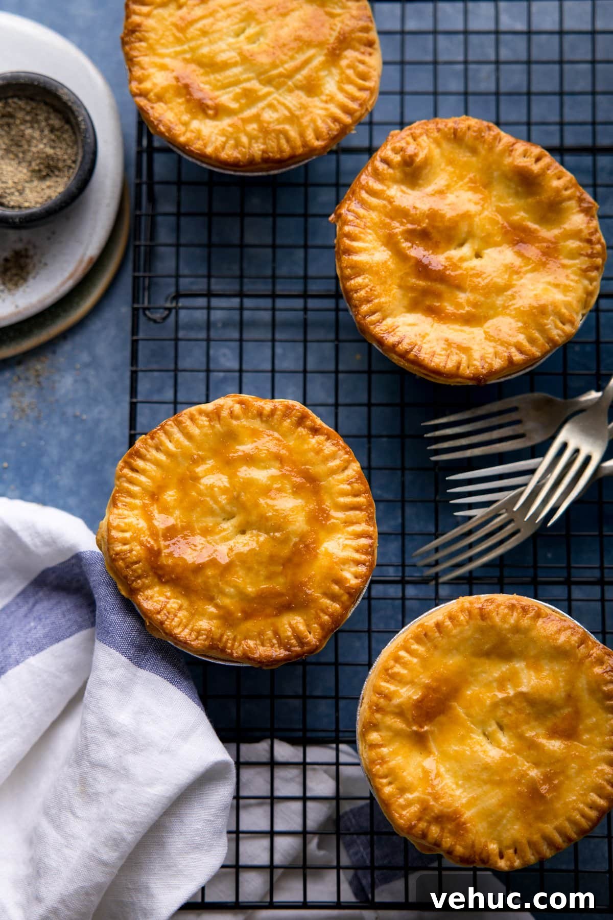 Chip Shop Style Individual Cheese and Onion Pies 7 Overhead image of 4 cheese and onion pies on a cooling rack on a blue surface.